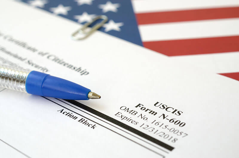 uscis form n-600 with pen and american flag